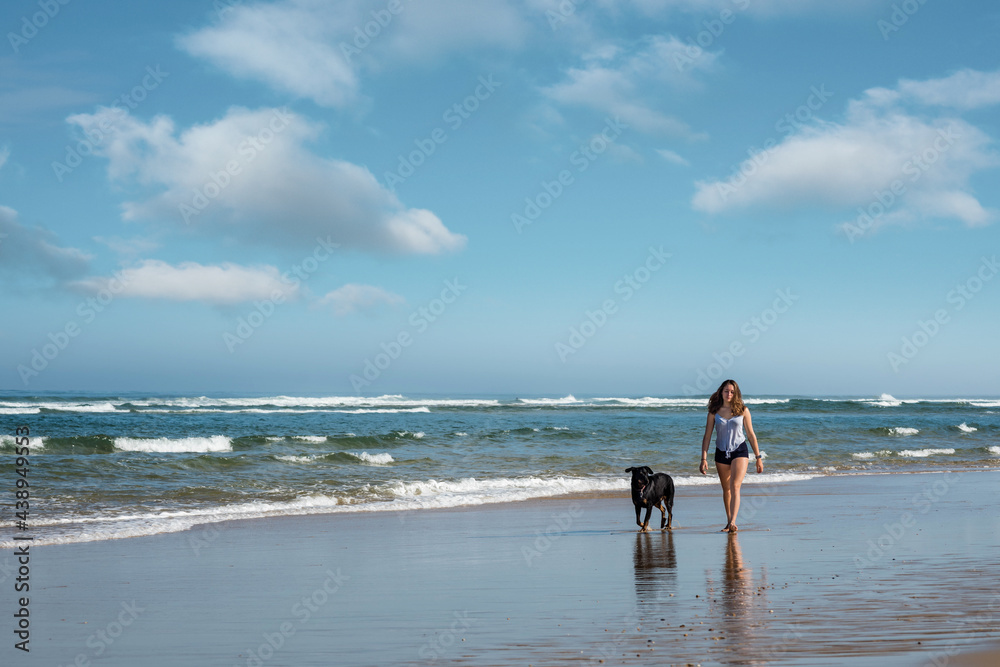 pretty young woman walking by the ocean with her dog