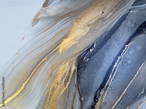 Abstract grey art with gold — black and white background with beautiful smudges and stains made with alcohol ink and golden paint. Grey fluid texture resembles marble, smoke, watercolor or aquarelle.
