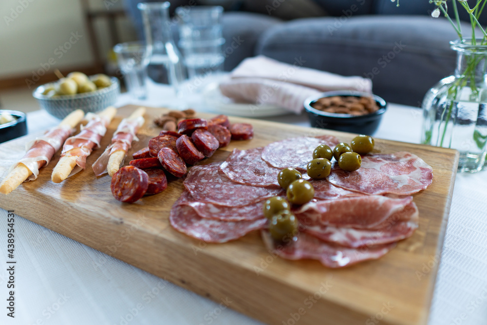 Side angle view over a charcuterie board set up on a table in a home interior setting. Food sharing concept in natural daylight