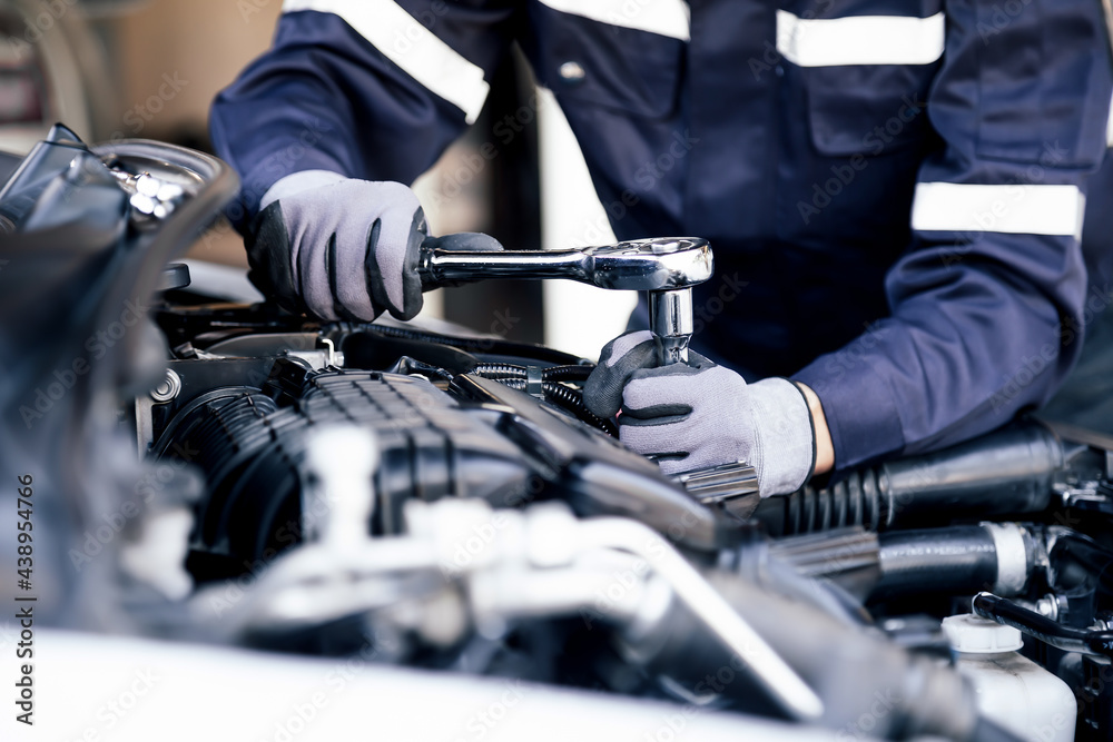 Professional mechanic working on the engine of the car in the garage. Car repair service. The concept of checking the readiness of the car before leaving. Professional mechanic working on the engine of the car in the garage. Car repair service. The concept of checking the readiness of the car before leaving.