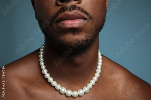 Obraz na plátně Cropped portrait of shirtless black man with pearl necklace over blue wall