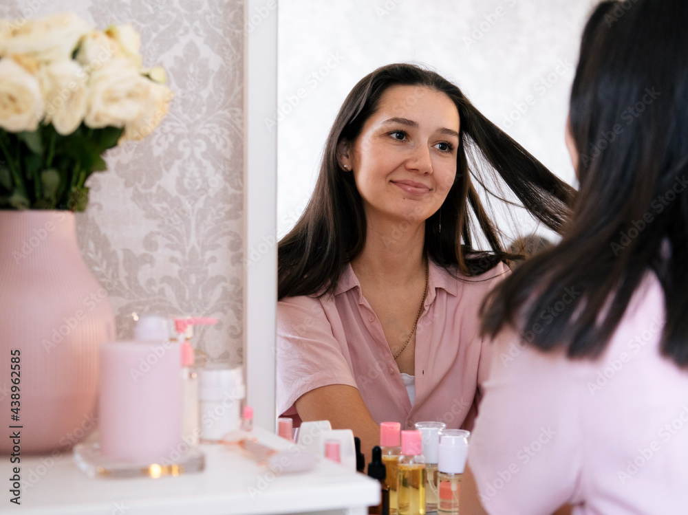Beautiful brunette woman looking in the mirror. Beauty concept. Beautiful brunette woman looking in the mirror. Beauty concept.