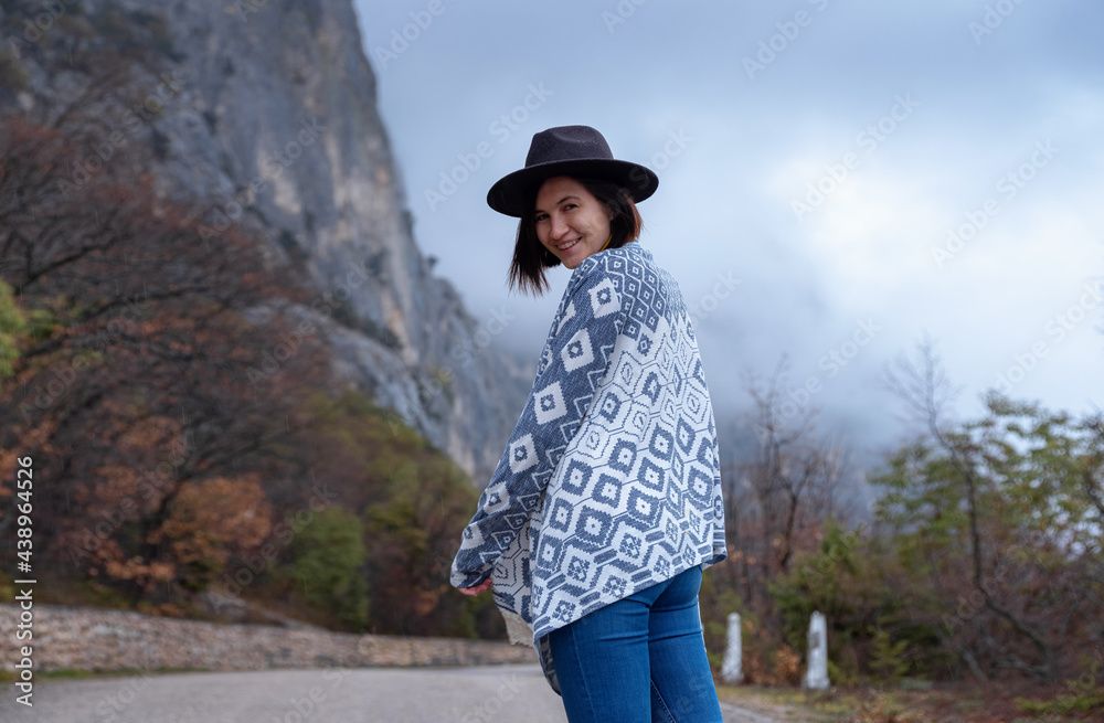 Stylish hipster woman in a hat walking down a mountain road
