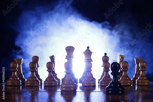 Wooden chess is a board game. Chess pieces on a dark background in smoke