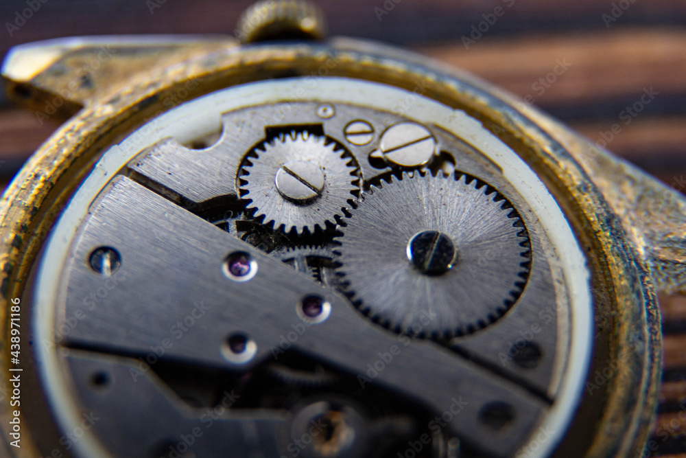 The movement of an old mechanical watch on a wooden background.
