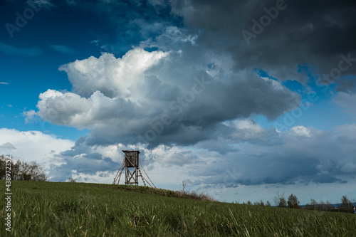 Wooden hunter high seat on field with heavy clouds on bacground