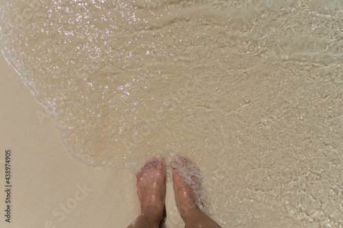 barefoot stand on sand beach with soft wave at morning. soft focus