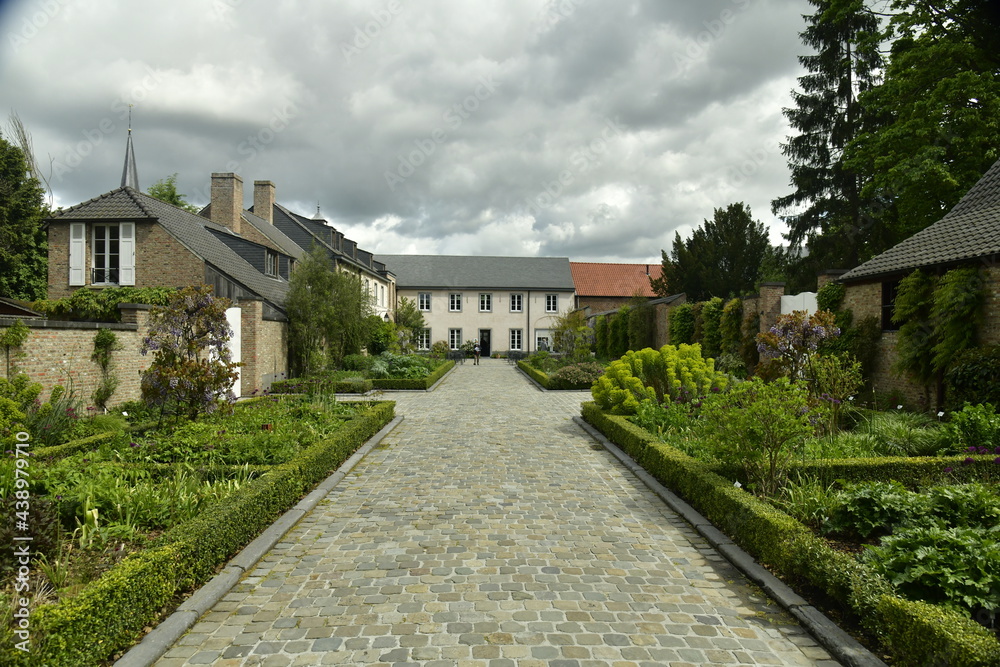 L'allée d'accès en pierres avec ses parterres de fleurs et coins de repos à l'arboretum de Wespelaar en Brabant Flamand 