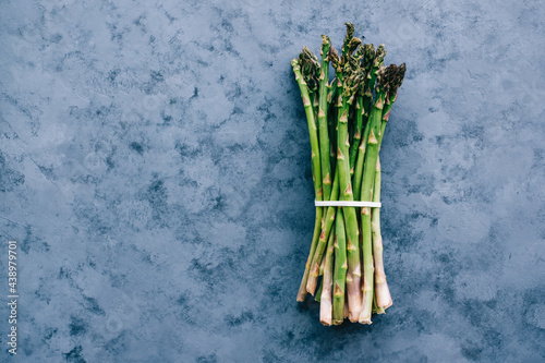 Asparagus bunch isolated on blue background, top view with copy space.