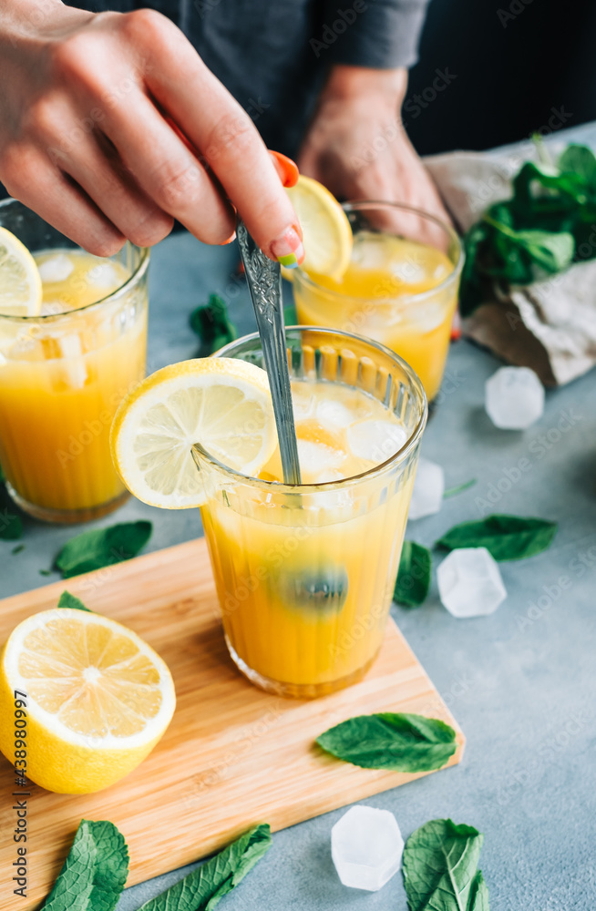 Female bartender cooking fresh lemonade with spoon in glass with ice. Female bartender cooking fresh lemonade with spoon in glass with ice.