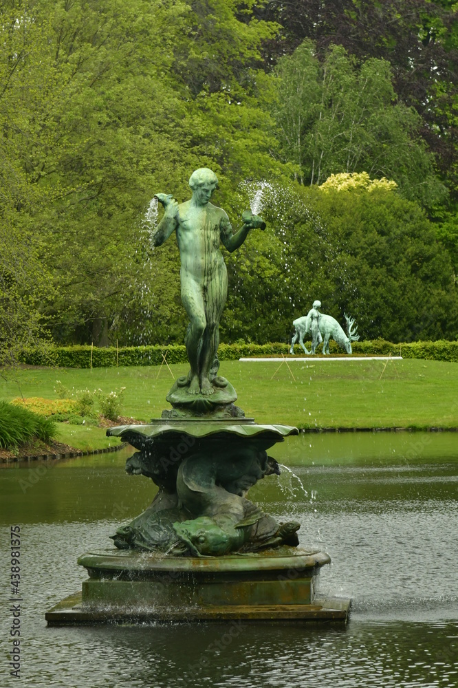 L'étang principal et sa statue-fontaine en bronze entouré de végétation luxuriante pendant une éclaircie à l'arboretum de Wespelaar en Brabant Flamand 