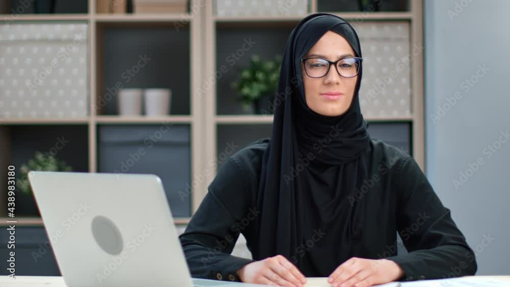 Portrait of modern ethnic Muslim young woman posing at home office workplace sitting at table Portrait of modern ethnic Muslim young woman posing at home office workplace sitting at table