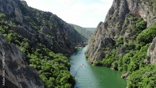 Drone view of Matka Canyon. Drone shot of a lake in a canyon in North Macedonia. Rocky green slopes. Transparent water surface of the lake. Mountain trail along the river. Lake in the mountains