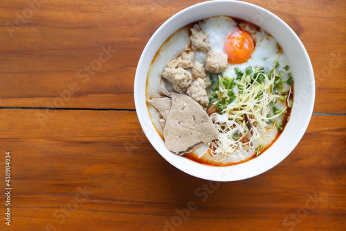 Congee, Rice soup, Rice porridge with egg in the bowl, Thai morning delicious food isolated on wooden background closeup.