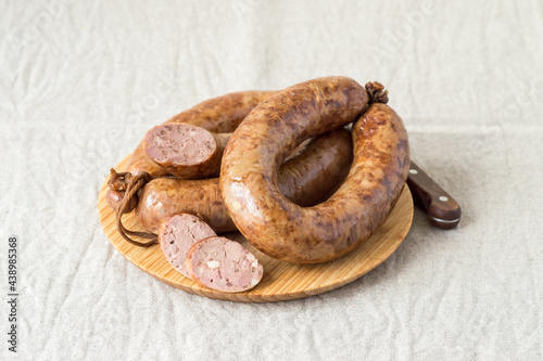 Homemade natural sausage on a wooden board on a light background with copy space. Selective focus.