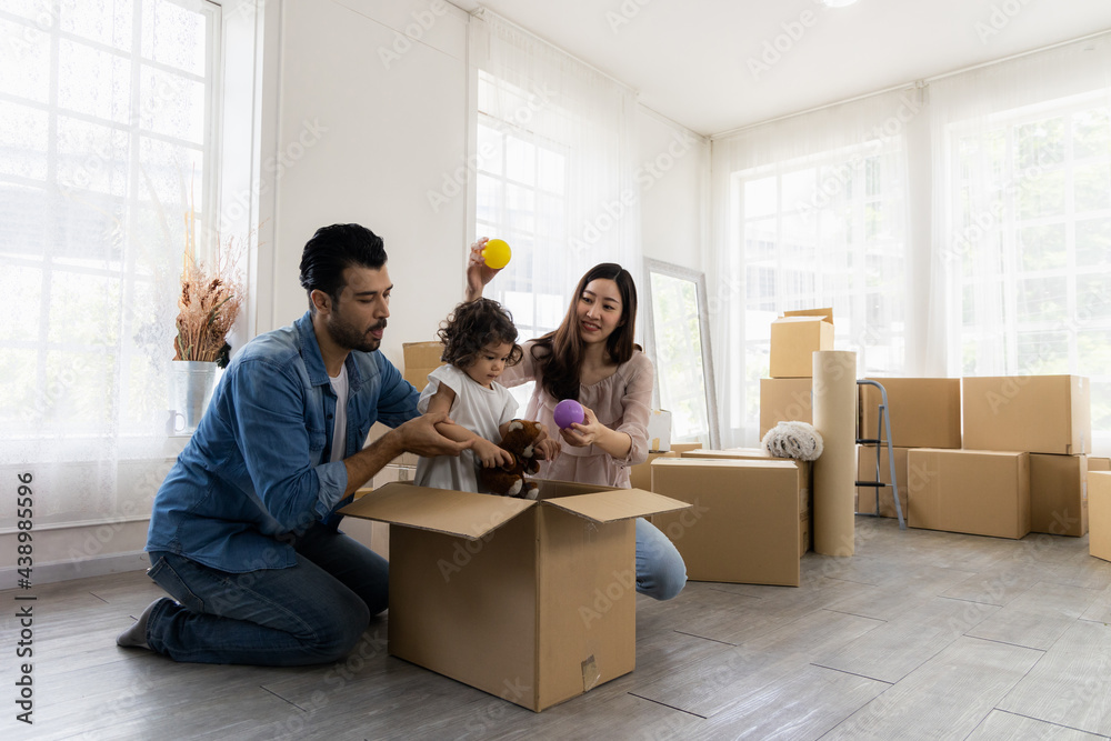 Daughter sits in a carton paper box playing with dad and mom. The family just moved to a new home. Parents and children have fun organizing things together. Daughter sits in a carton paper box playing with dad and mom. The family just moved to a new home. Parents and children have fun organizing things together.