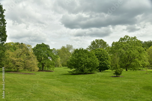 Fototapeta Naklejka Na Ścianę i Meble -  Nuages gris et parfois sombres contrastant avec la beauté verte des feuillage des arbres et pelouses de l'arboretum de Wespelaar en Brabant Flamand 