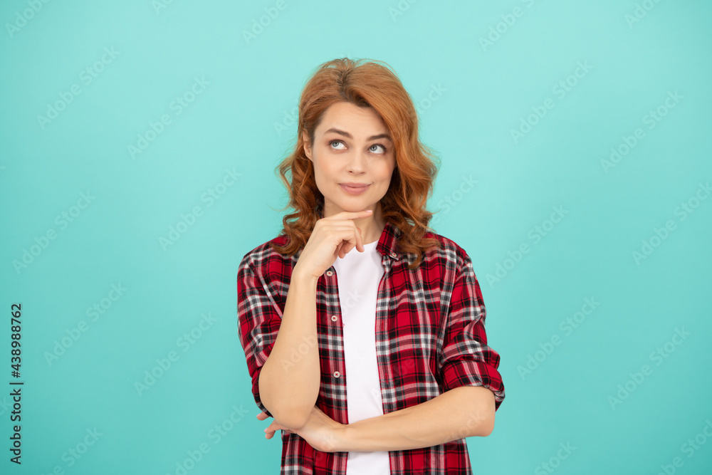 thinking redhead woman with curly hair in checkered casual shirt, thoughtful