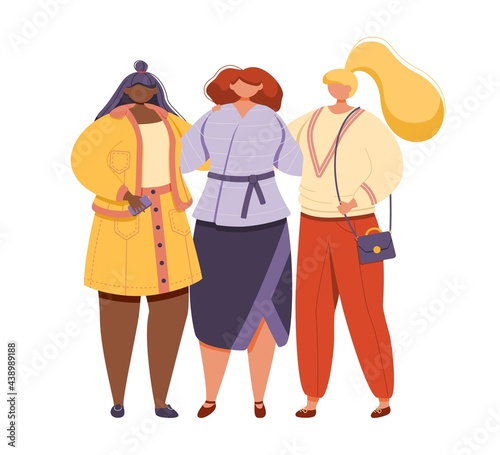 Three female friends in modern and fashionable clothes stand and embrace one another.