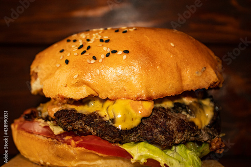 juicy burger with beef cutlet, sauce and vegetables, on a blurred background from the boards