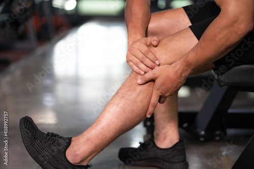 Close up shot at body part of young adult Caucasian men feeling painful from knee muscle injury after workout with weight lifting, Muscle injured from workout or exercise for weight training.