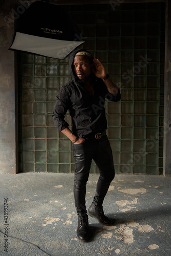 Stylish african handsome man in black clothes standing and posing in urbam interior of concrete and glass