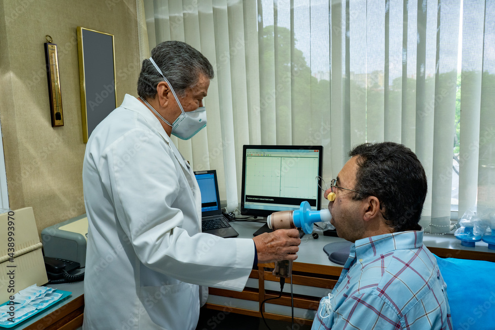 Obraz premium Mature man performing pulmonary function test and spirometry in doctor office