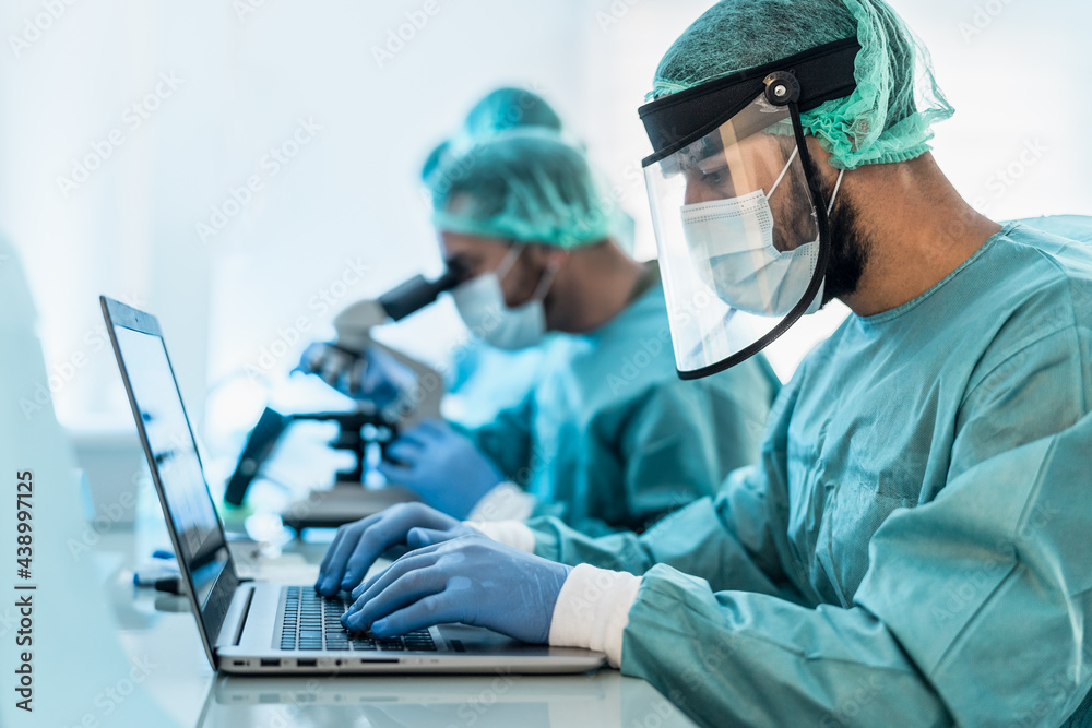 Doctors working in research laboratory using computer and examining microorganisms through microscope - Science and technology concept Doctors working in research laboratory using computer and examining microorganisms through microscope - Science and technology concept