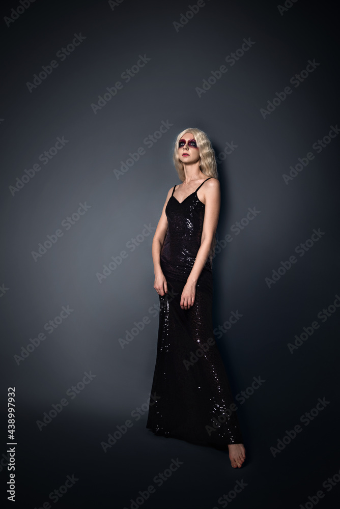 beautiful young woman in a black tight dress on a black background with dark makeup