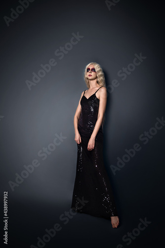beautiful young woman in a black tight dress on a black background with dark makeup