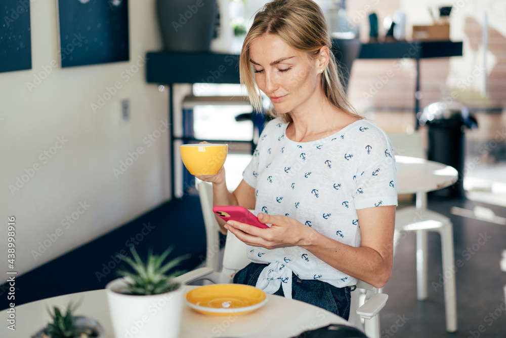 Young beautiful blonde woman smiling uses social media in a mobile phone.