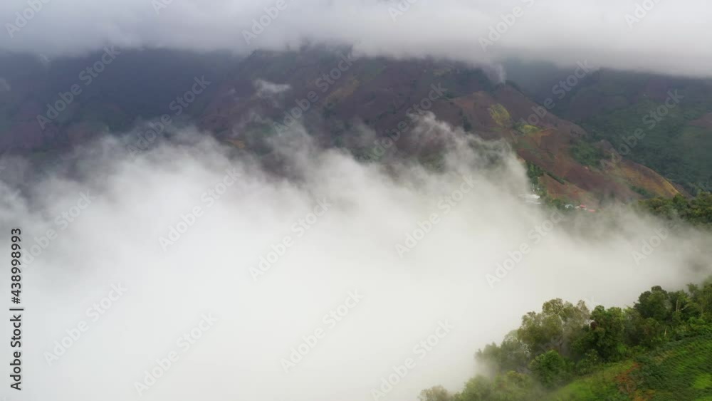Aerial view flying above lush green tropical rain forest mountain with rain cloud cover during the rainy season on the Doi Phuka Mountain reserve national park. In, the northern Thailand