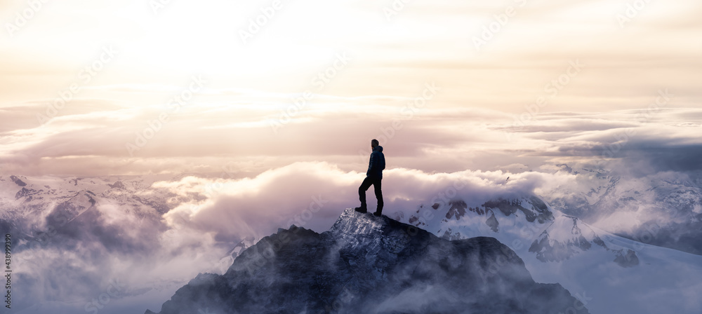 Magical Fantasy Adventure Image Composite of Man Hiking on top of a rocky mountain peak. Background Landscape from British Columbia, Canada. Colorful Sunset or Sunrise Colorful Sky