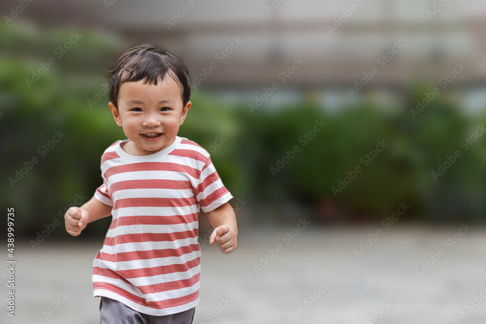 © TimmyTimTim - Portrait of an asian boy (toddler) running toward and smiling with happy and fun face while playing outdoor. A Child wear striped shirt in red and white color. Head and hair is wet by sweat.