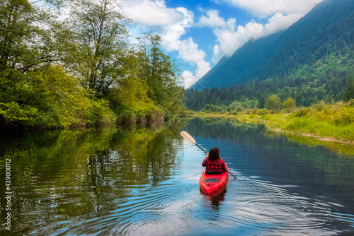 Adventure Caucasian Adult Woman Kayaking in Red Kayak surrounded by Canadian Mountain Landscape. Blue Sky Art Render. Widgeon Valley, Pitt Meadows, Vancouver, British Columbia, Canada.