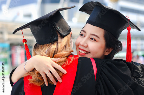 фотографія Two happy graduated women students with square academic hat cap hugging each oth