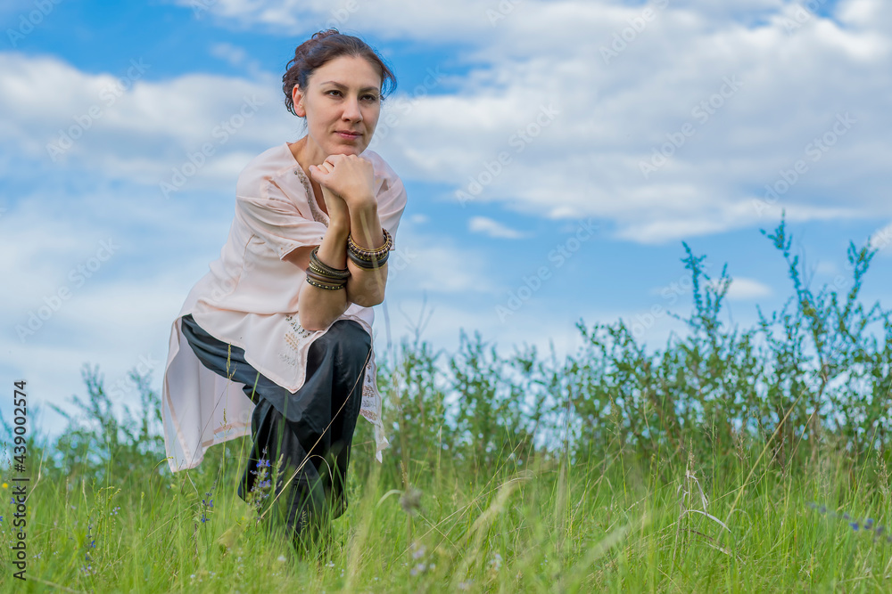 Young woman performs yoga exercises. Stands on a green field against the blue summer sky. Healthy lifestyle. Young woman performs yoga exercises. Stands on a green field against the blue summer sky. Healthy lifestyle.