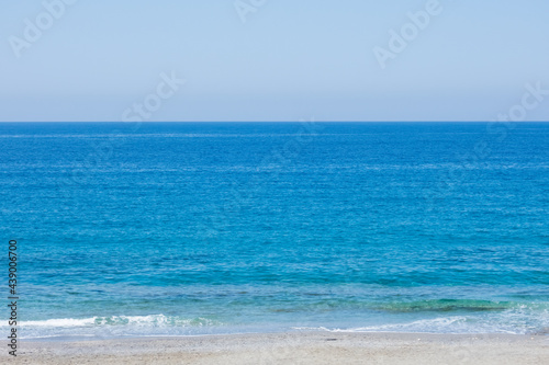 Bright blue mediterranean sea with strip of beach on sunny summer day