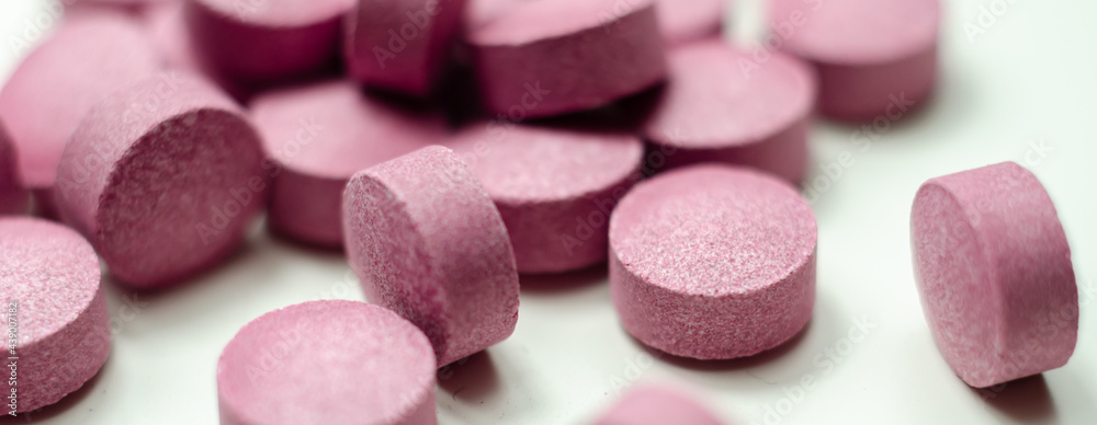 Purple pills scattered on a white background, food supplements which includes acai berries Purple pills scattered on a white background, food supplements which includes acai berries