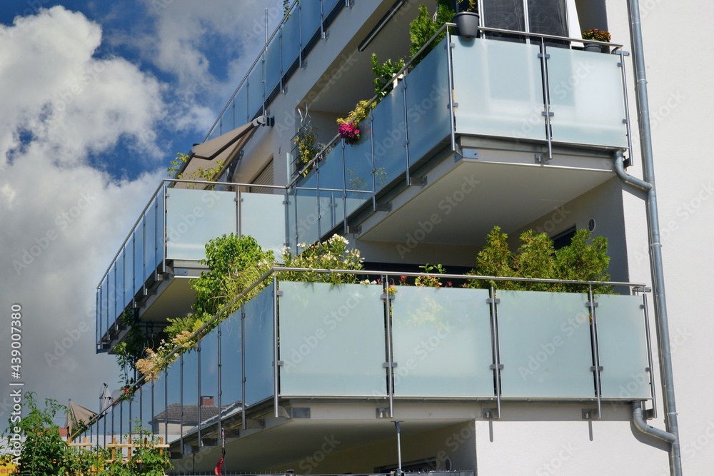 Fototapeta premium Balkon mit Edelstahl-Geländer und Sichtschutz aus Milchglasplatten an der Fassade eines modernen Mehrfamilien-Wohnhauses