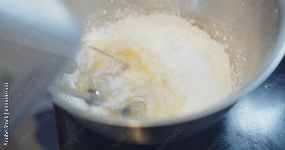 Slow motion of automatic flour mixing machine mixing kneading ingredient of cake is egg, butter, flour and sugar in the bowl, preparing delicious flour dough cream to make homemade donuts cake Slow motion of automatic flour mixing machine mixing kneading ingredient of cake is egg, butter, flour and sugar in the bowl, preparing delicious flour dough cream to make homemade donuts cake