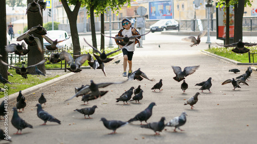 Boy playing with pigeons. A child in sunglasses on a walk