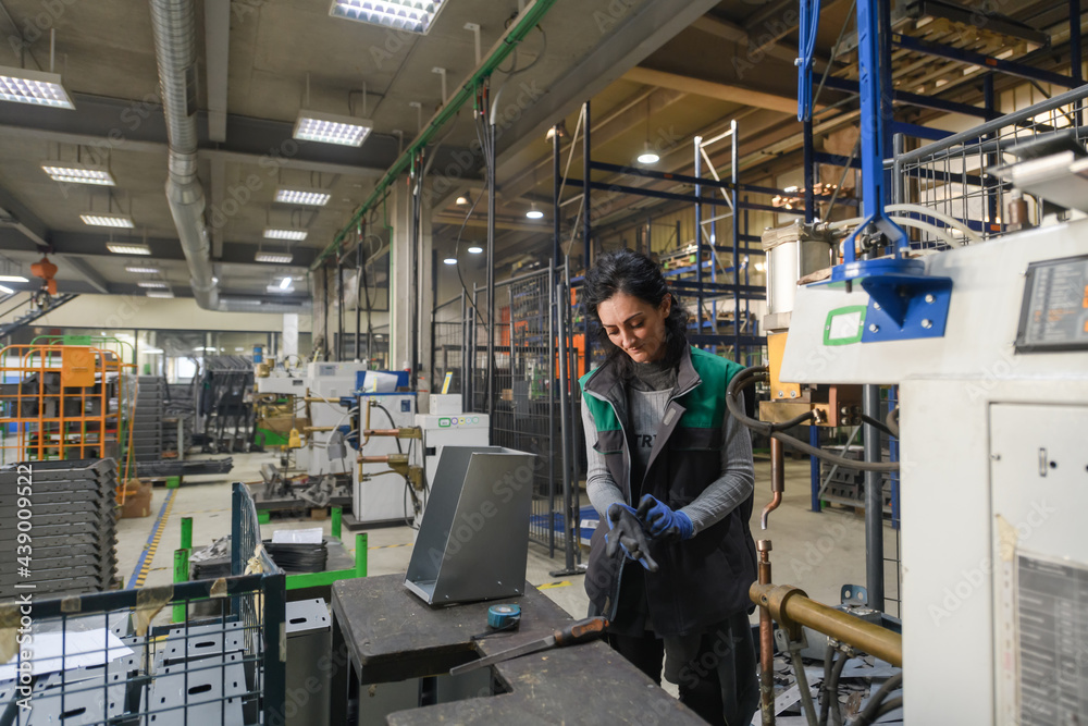 a woman working in a modern metal factory assembles parts for a new machine a woman working in a modern metal factory assembles parts for a new machine