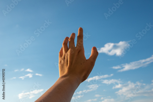 Hand reaching for the sky. Hand on evening blue sky background