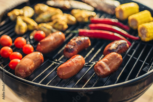 Delicious assorted grilled meat and sausages, with grilled vegetables with smoke and flame outdoors in the park in