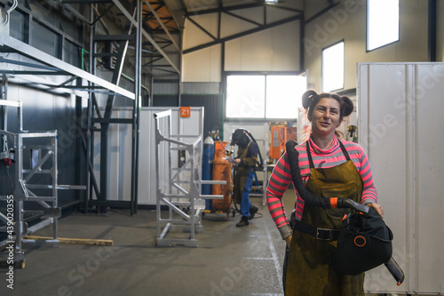 a portrait of a women welder holding a helmet and preparing for a working day in the metal industry