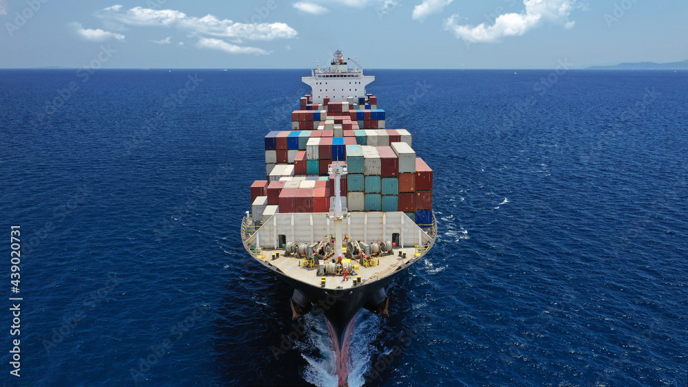 Fototapeta premium Aerial drone photo of industrial colourful vessel carrying heavy truck size containers cruising the Mediterranean deep blue sea