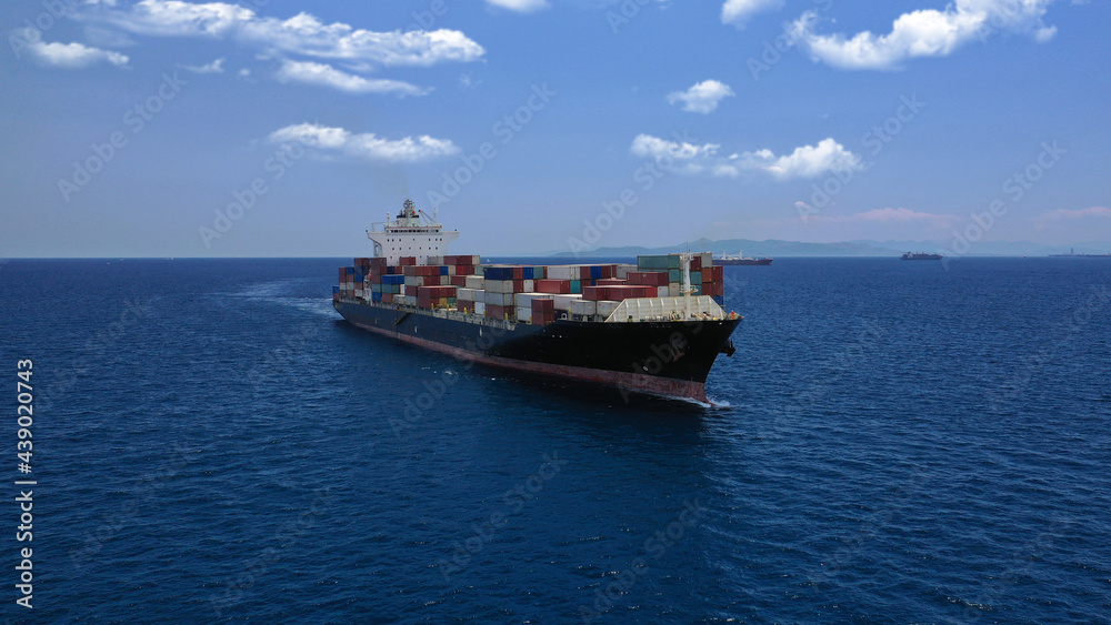 Aerial drone photo of industrial colourful vessel carrying heavy truck size containers cruising the Mediterranean deep blue sea Aerial drone photo of industrial colourful vessel carrying heavy truck size containers cruising the Mediterranean deep blue sea