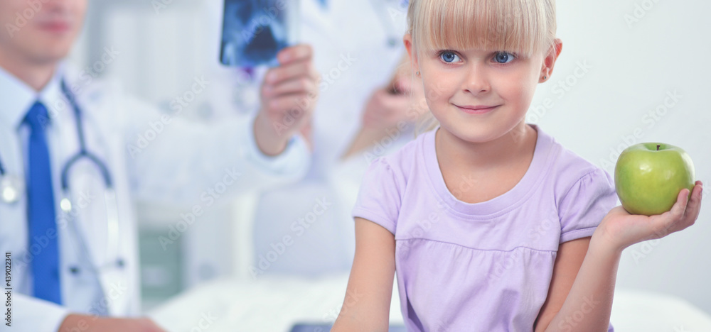 Child and medicine concept - female doctor giving an apple to little girl Child and medicine concept - female doctor giving an apple to little girl