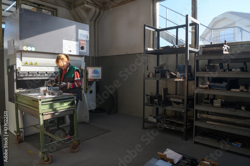 woman working in a modern factory and preparing materia for a CNC machine. 